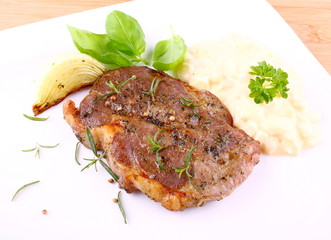 Grilled steak meat with onion, potato salad and basil
