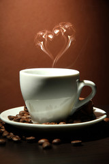 Cup of coffee with smoke in shape of heart on brown background