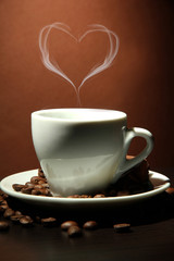 Cup of coffee with smoke in shape of heart on brown background
