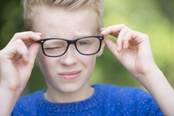 Blond teenager boy with glasses outdoor