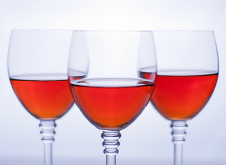 Three transparent wineglasses with rose wine. White background