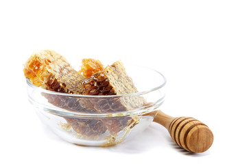 Honey comb in a glass bowl and wooden stick, isolated on white b