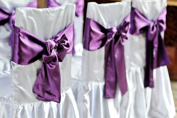 The chairs are decorated with purple bows
