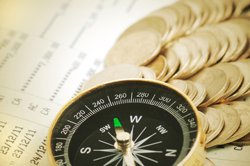 Coins and compass on bank book account in vintage color