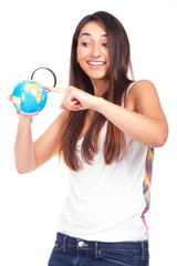 Pretty female holding a globe and using a magnifying glass while