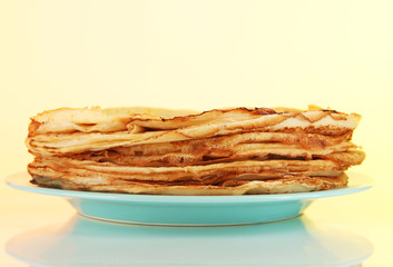 Pancakes on plate on yellow background