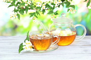 Cup of tea with jasmine, on wooden table, on bright background