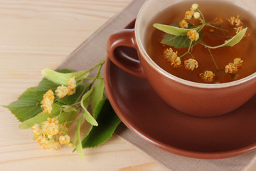 Cup of tea with linden on napkin   wooden table