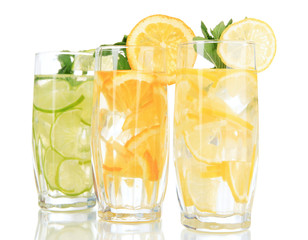 Glasses of fruit drinks with ice cubes isolated on white