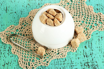 Unrefined sugar in white sugar bowl on wooden background