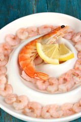 Shrimps with lemon on plate on blue wooden table close-up