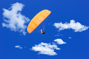 paraglider flying in a blue sunny sky with clouds - obrazy, fototapety, plakaty