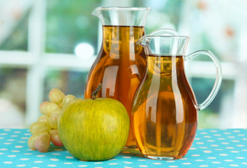 Apple juice in pitchers on table in room