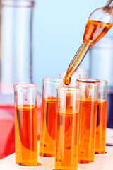 Laboratory pipette with drop of color liquid over glass test