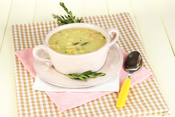 Nourishing soup in pink pan on wooden table close-up