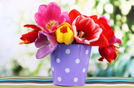 Beautiful tulips in bouquet on table on bright background