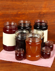 Tasty jam in banks on wooden background