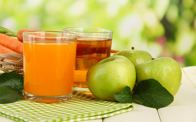 Glasses of juice, apples and carrots