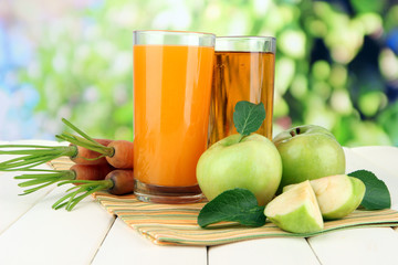 Glasses of juice, apples and carrots