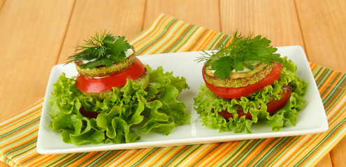 Tasty roasted marrow and tomato slices with salad leaves,