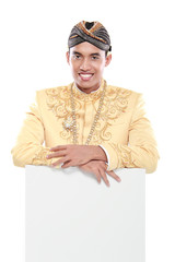 man wearing traditional dress of java holding blank board