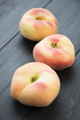 Donut or saturn peaches on black wooden boards, vertical shot