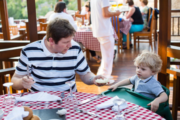 Young father and son having breakfast together in summer