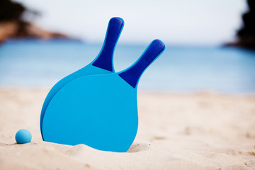 Fototapeta na wymiar blaue beachball schläger im sand am meer