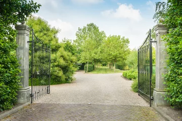Fotobehang Opened black wrought iron gate of a large estate © Ruud Morijn