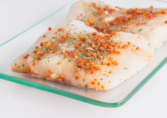 spicy cod pieces ready to be cooked in glass tray
