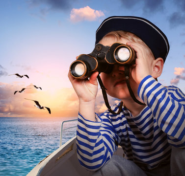 Sailor boy with binoculars in the boat