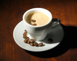 Cup of coffee with coffee beans on wooden background