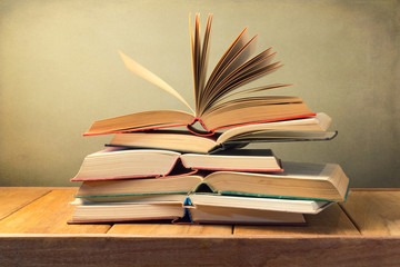 Fototapeta premium Open old books on wooden table over grunge background