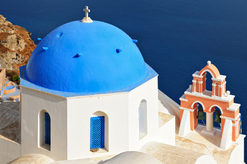 Iconic church with blue cupola and pink bell tower in Oia