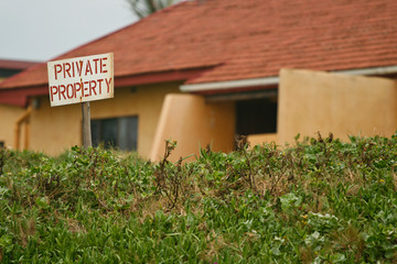 Private property sign with a residential house in the background