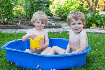 Two sibling boys having fun with water in summer