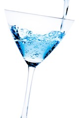 filling a glass with blue cocktail tilted and bubbles