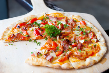 Pizza with bacon, garlic and dried chilli on wooden spatula