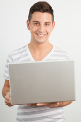 Young man smiling and using a laptop
