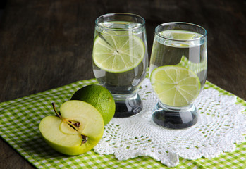 Glasses of cocktail with lime on napkin on dark wooden table