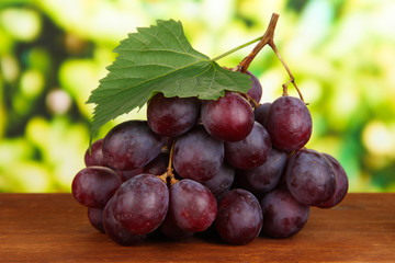 Ripe delicious grapes on table on bright background