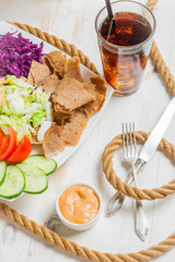 Kebab on a plate next to cold beverage