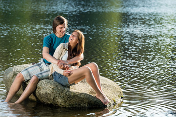 Couple sitting on rock by the lake