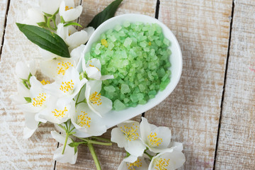 Sea salt in bowl with jasmine on wooden background