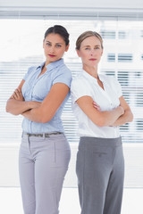 Fototapeta premium Serious businesswomen standing back to back