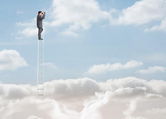 Businessman standing on a ladder over the clouds