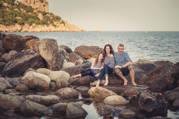 Family in striped shirts on the rocks near the sea