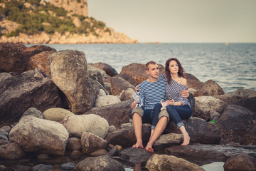 Fototapeta na wymiar Family in striped shirts on the rocks near the sea
