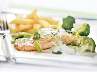 baked salmon served on a plate with vegetables and fries