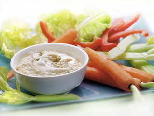 raw vegetables served on a plate with a dip sauce..